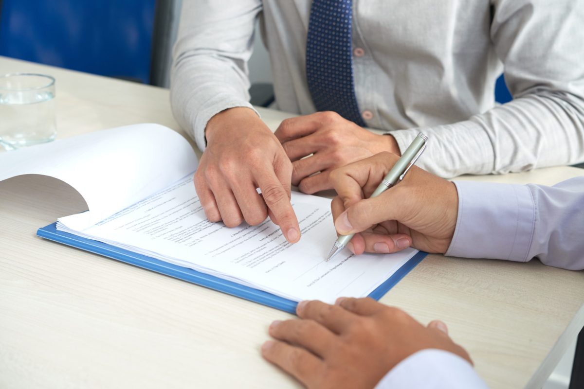 Businessman showing his partner where to sign the contract